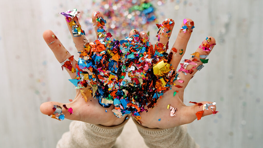 Kädet, jotka lähettävät ilmaan glittersilppua.